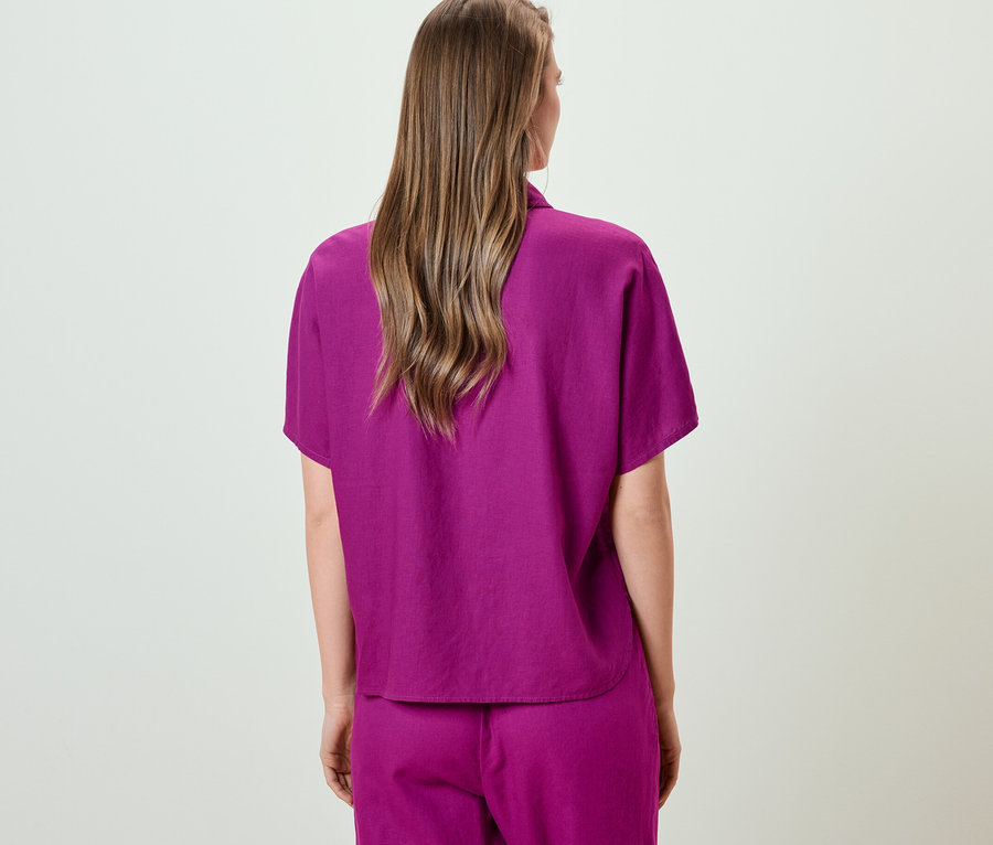 Pohľad zozadu na ženu v ľanovej blúzke.