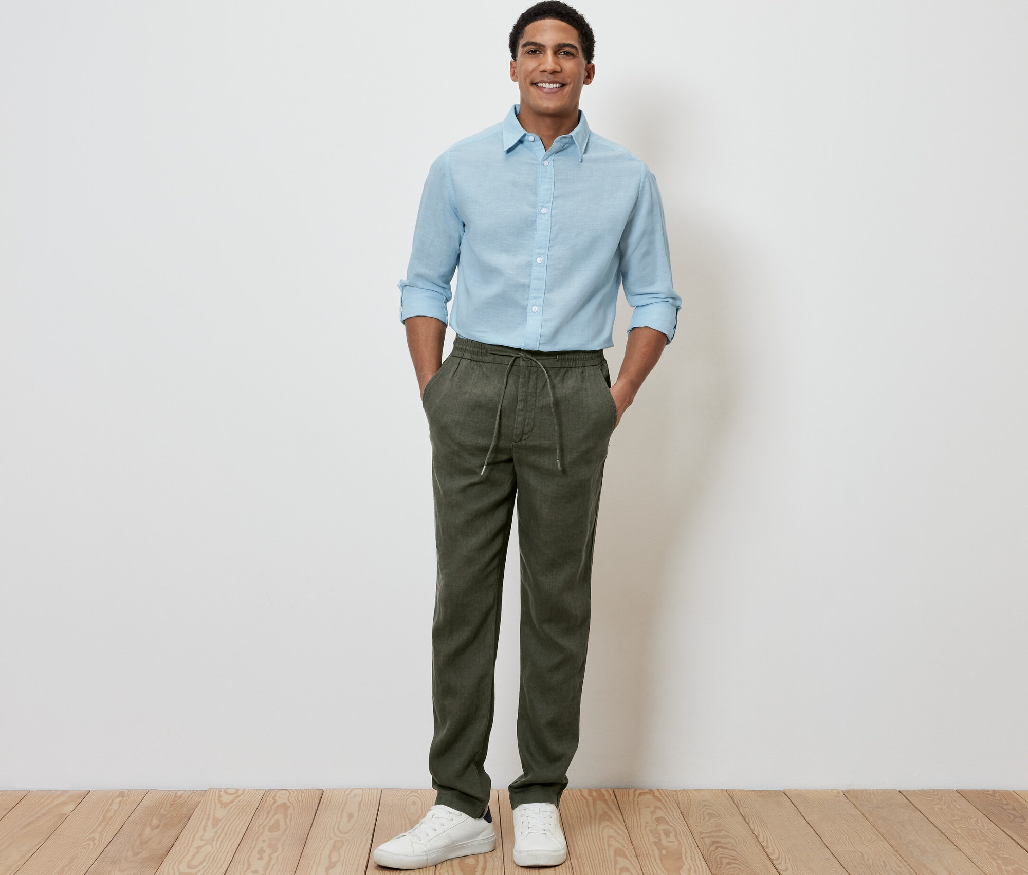 Muž stojí a má ruky vo vreckách ľanových nohavíc chino khaki.
