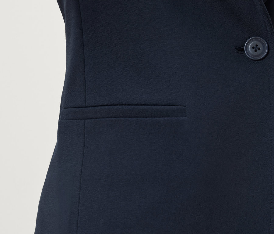 Detail tmavomodrého blejzra s gombíkom a vreckom.