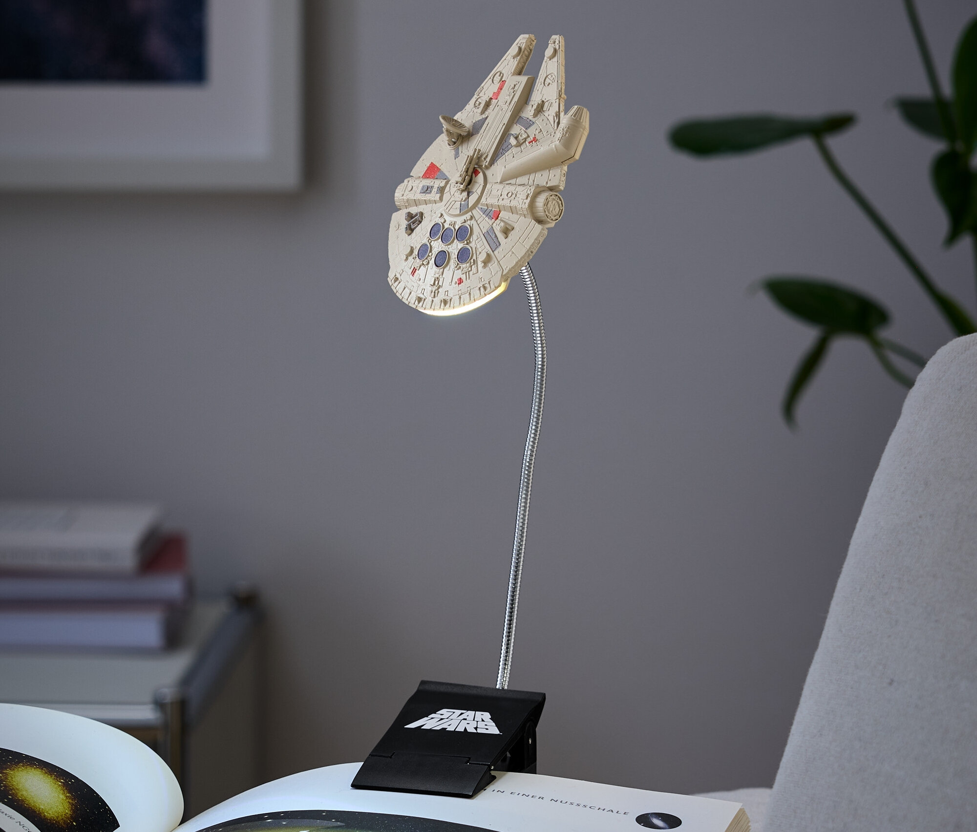 Lampa v tvare Millenium Falcon pripevnená na knihe.