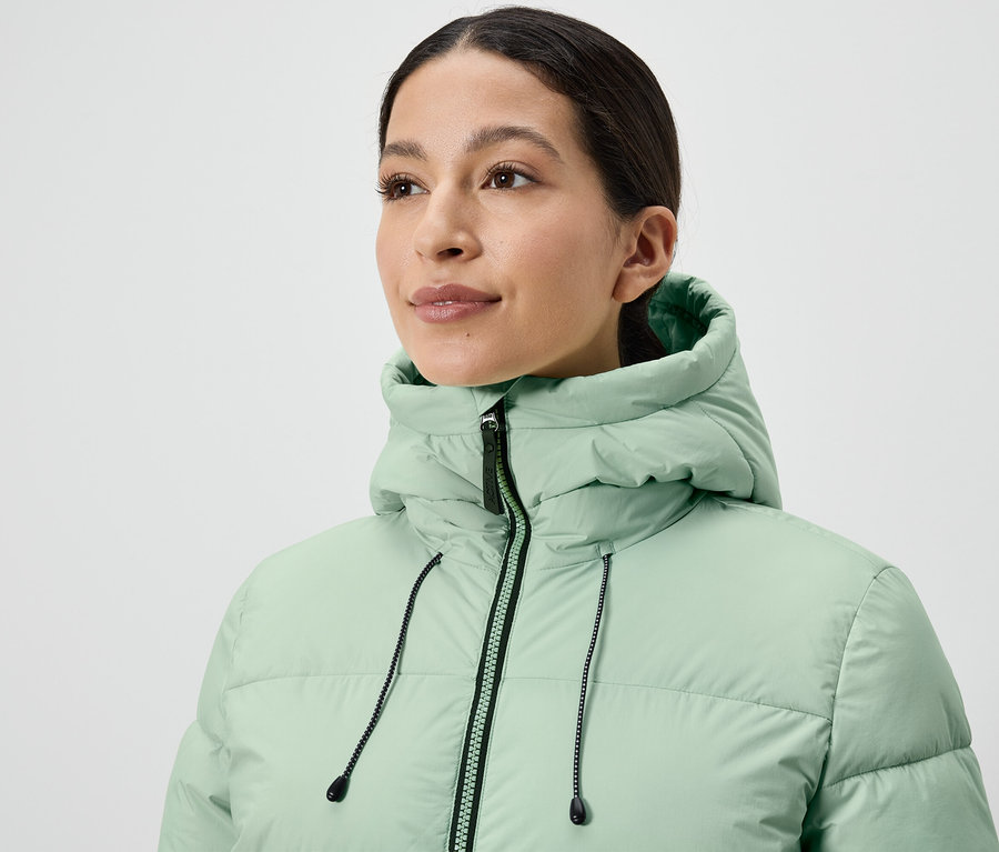 Žena má na sebe svetlozelenú páperovú bundu.