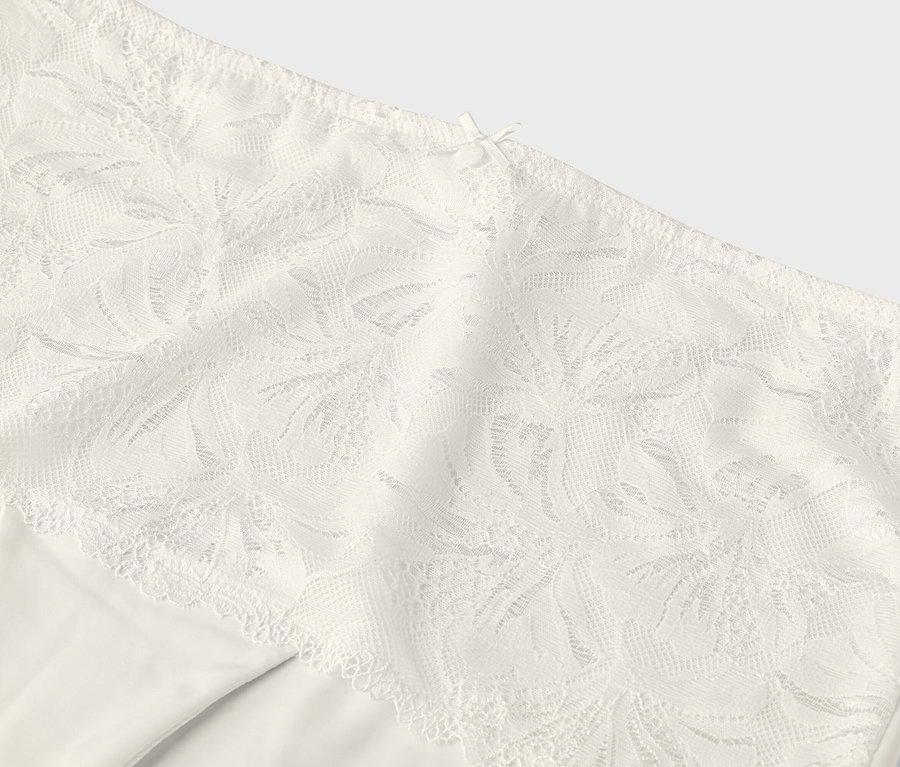 Detailný záber na krémové nohavičky s čipkovaným lemom.