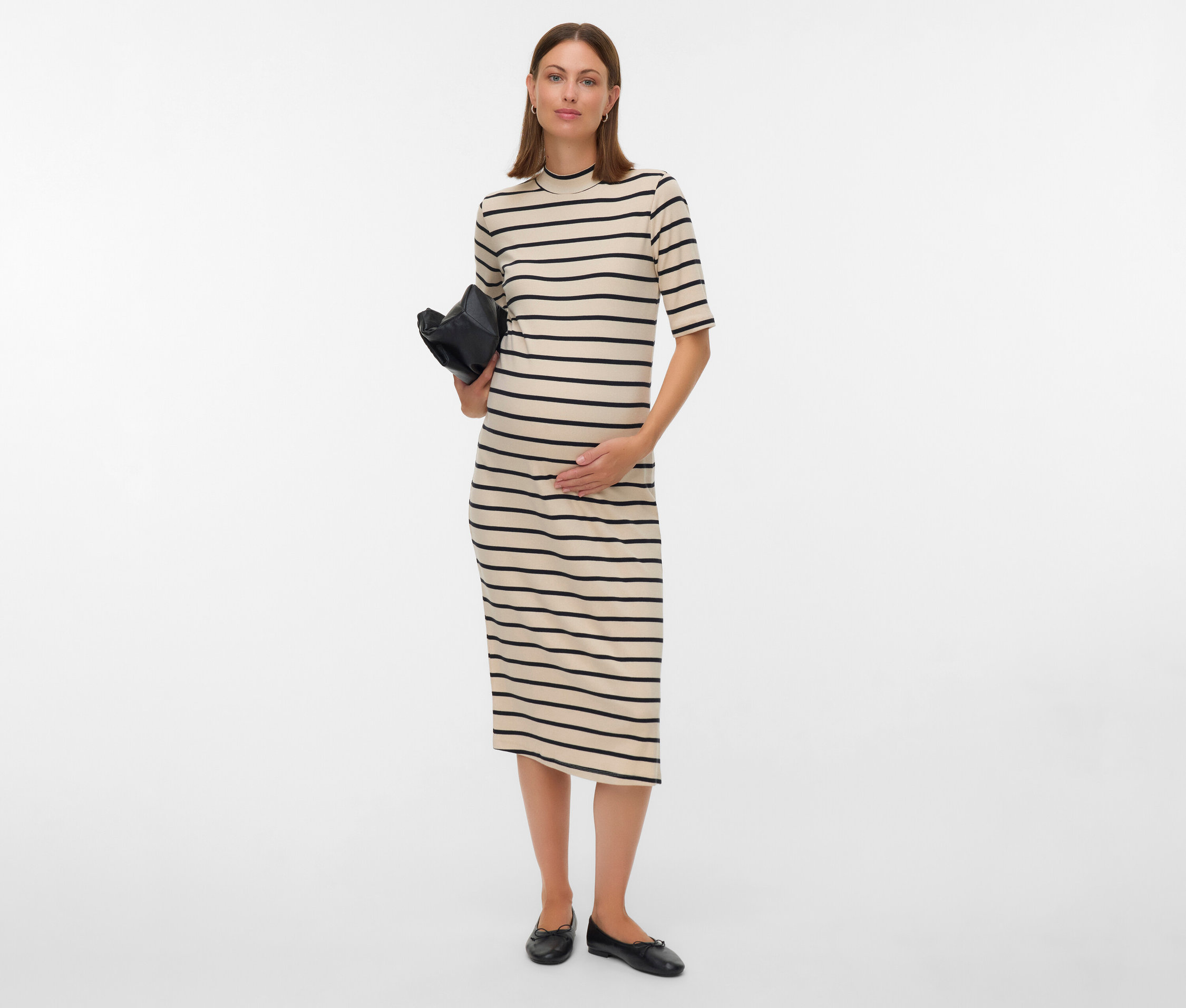 Tehotná žena v pruhovaných šatách drží čiernu kabelku.