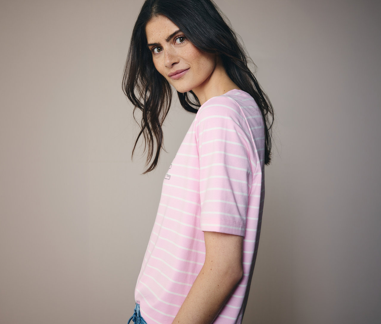 Žena sa pozerá cez plece a má na sebe ružovo-biele pásikavé tričko CECIL.