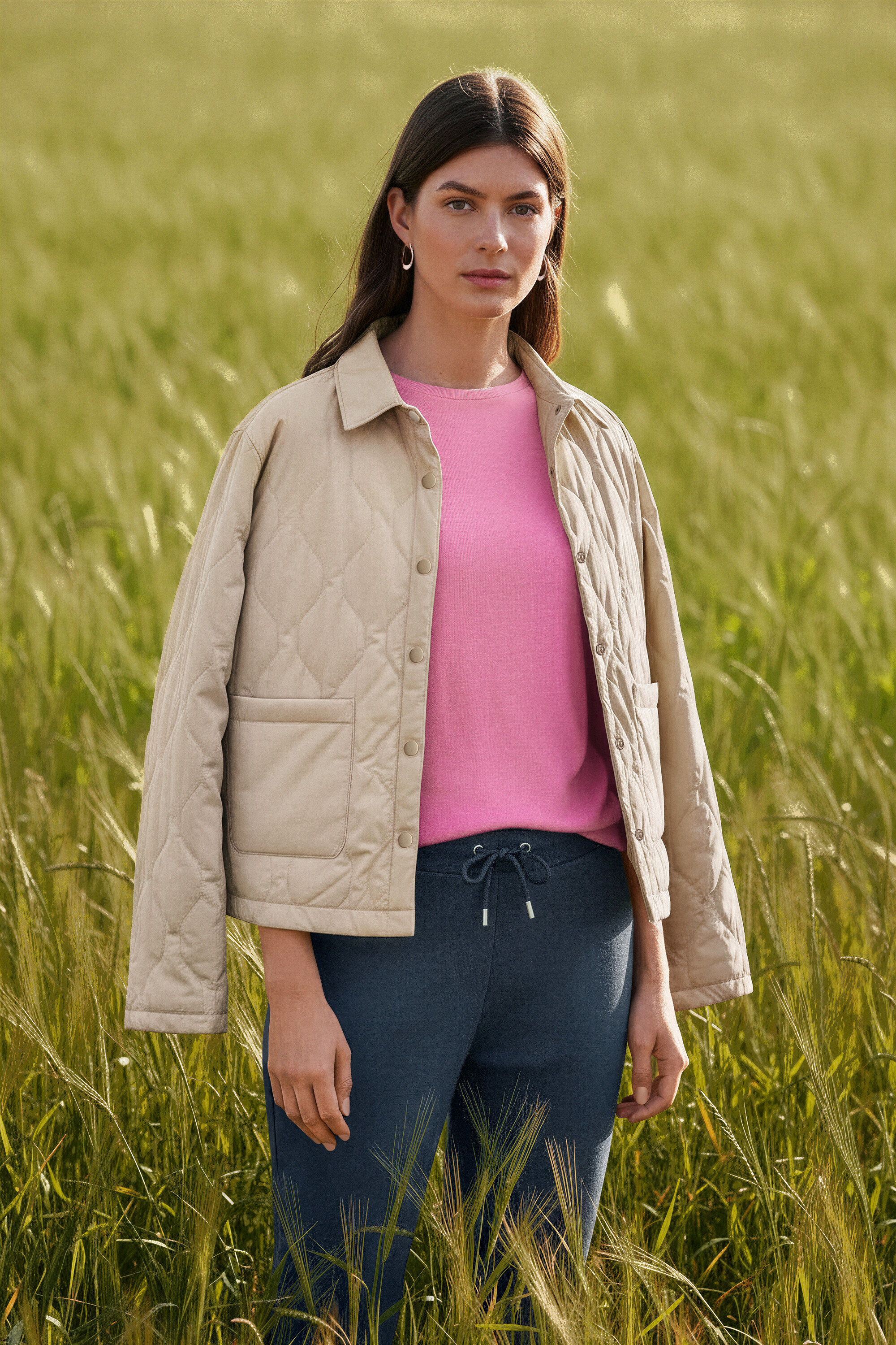 Žena stojí v poli a má kruhové náušnice Wave.