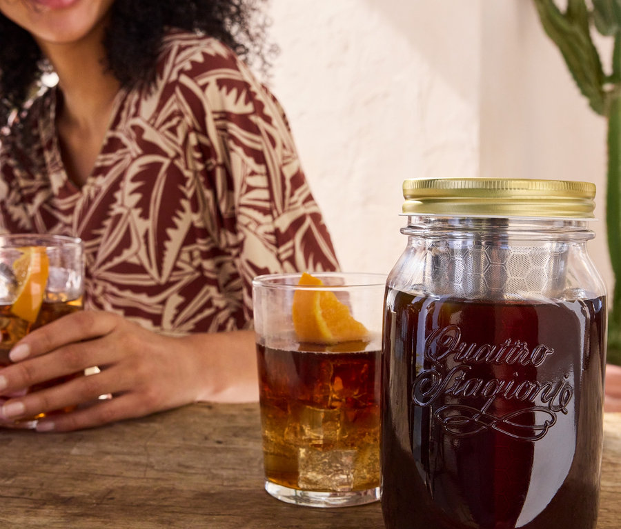 Žena drží pohár s nápojom vedľa pohára na studenú kávu cold brew »BrewJar« a džersejových šiat s potlačou.