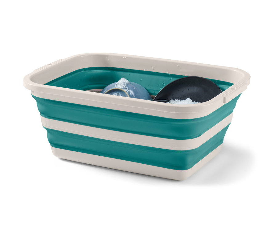 Špinavý riad v skladacom koši na bielizeň a pranie v zeleno-bielej farbe.