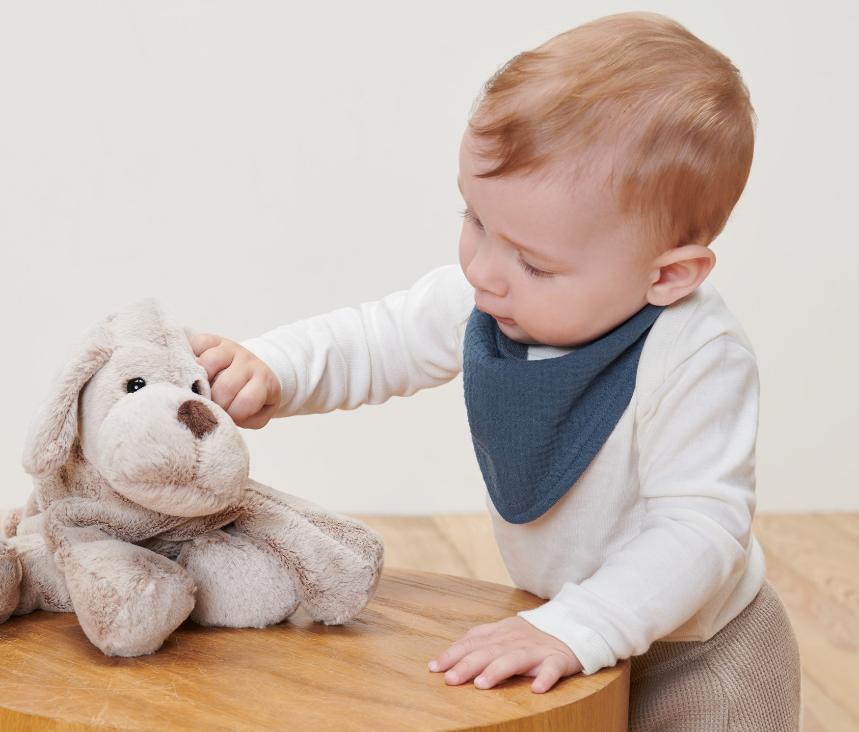 Dieťa sa hrá s plyšovým psom na drevenom stolíku a má na sebe Mušelínové šatky pre bábätká a dojčence, 2 ks.