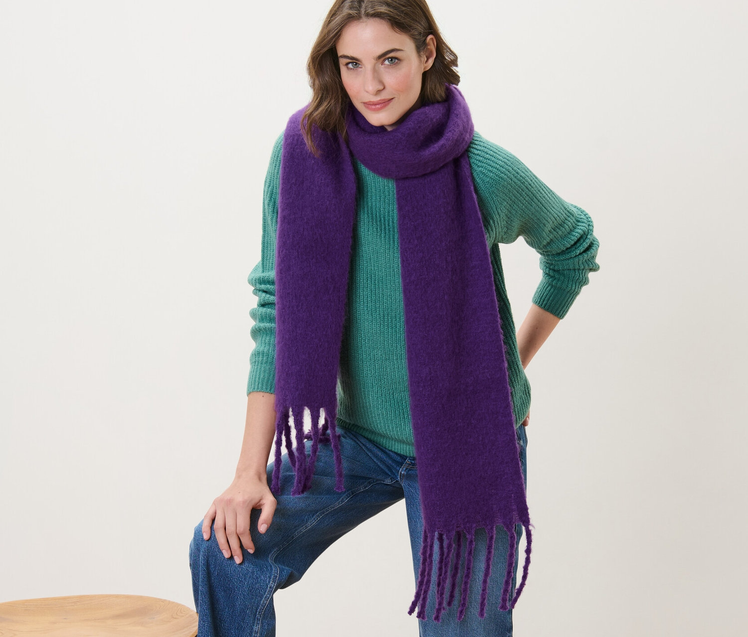 Žena pózuje s fialovým tkaným šálom.