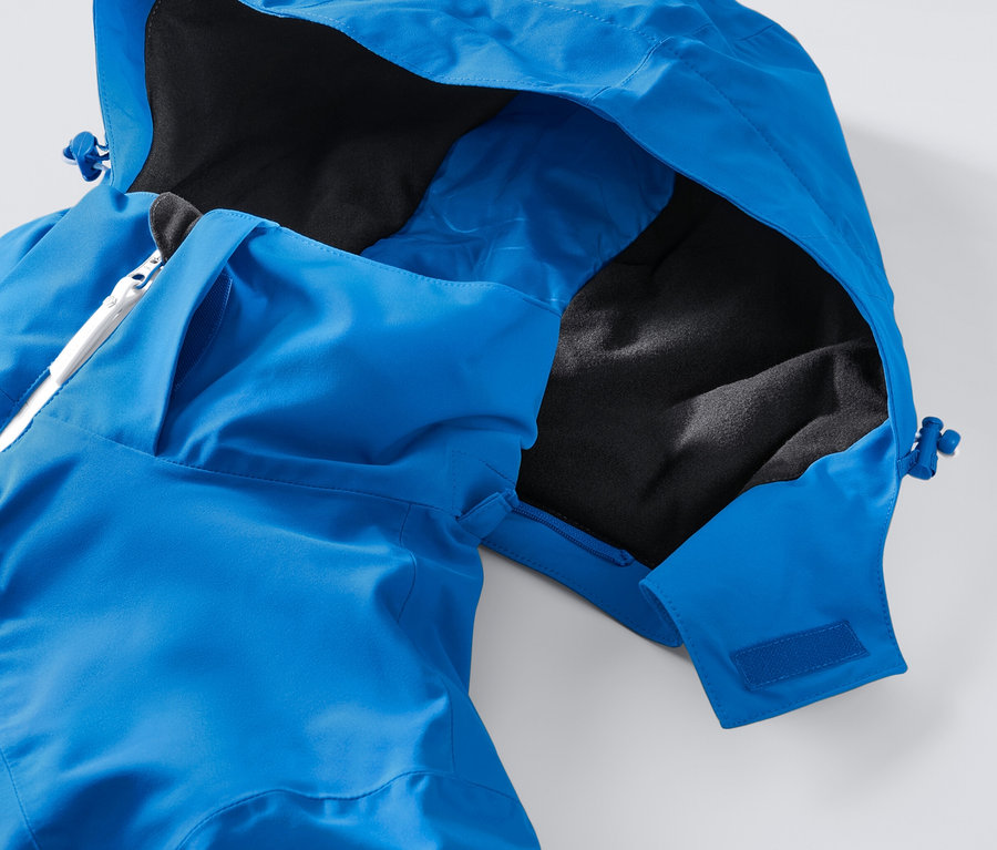Detail modrej high-tech lyžiarskej bundy s kapucňou a bielym zipsom.