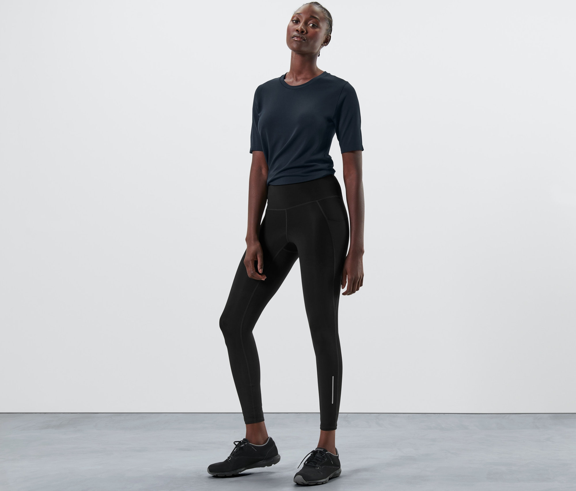 Žena pózuje v športových čiernych legínach.