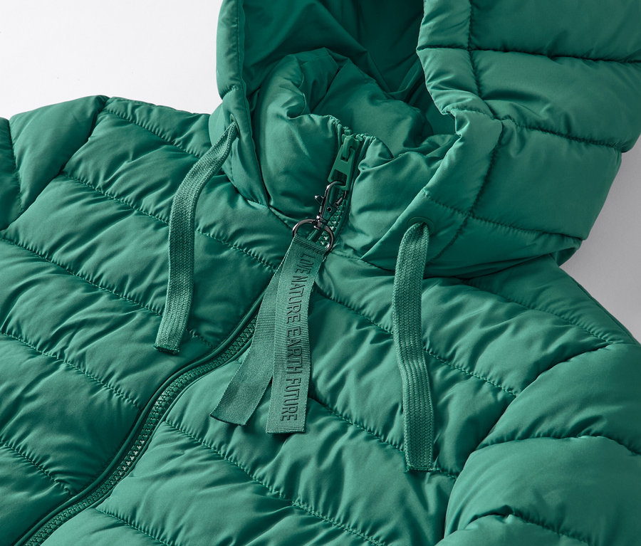 Detail zelenej prešívanej bundy s kapucňou.
