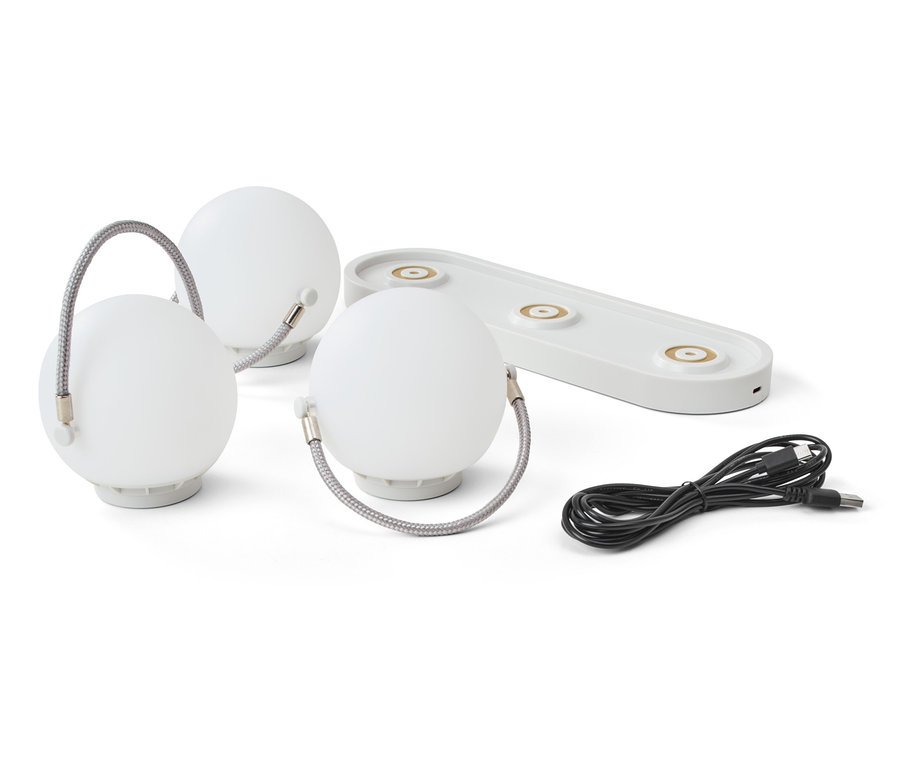 Tri stolové svietidlá s akumulátorom, nabíjacia stanica a kábel na bielom pozadí.