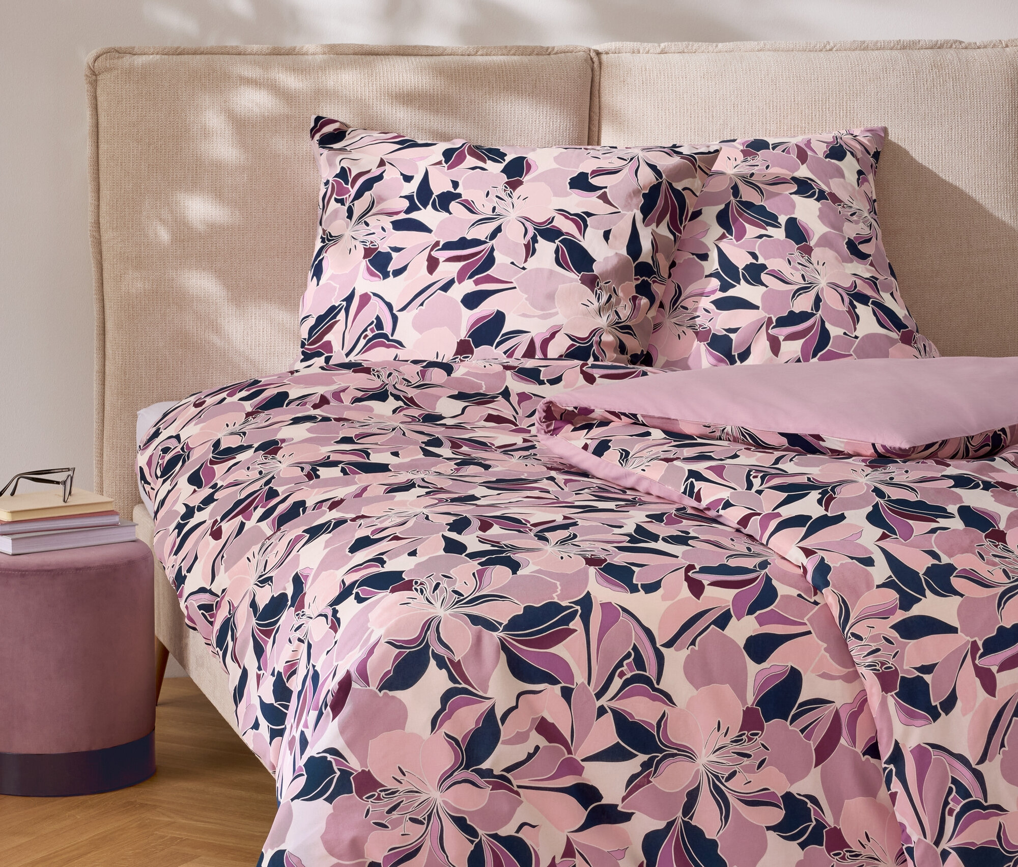 Kvetinové obliečky s vankúšmi na posteli s čelom a nočným stolíkom.