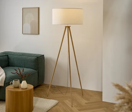 Obývacia izba s pohovkou, dreveným stolíkom, lampou so statívom a umeleckým dielom na stene.