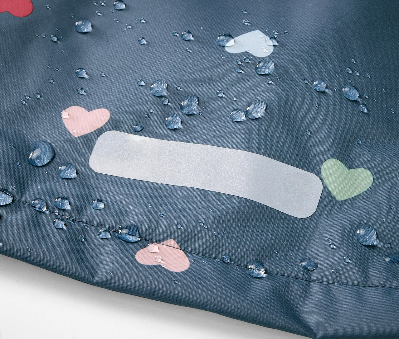 Detail detskej termo bundy do dažďa s motívom srdiečok a kvapkami vody.