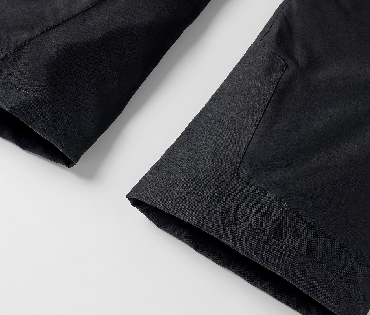 Detail čiernych nohavíc s vreckom na bielom pozadí.