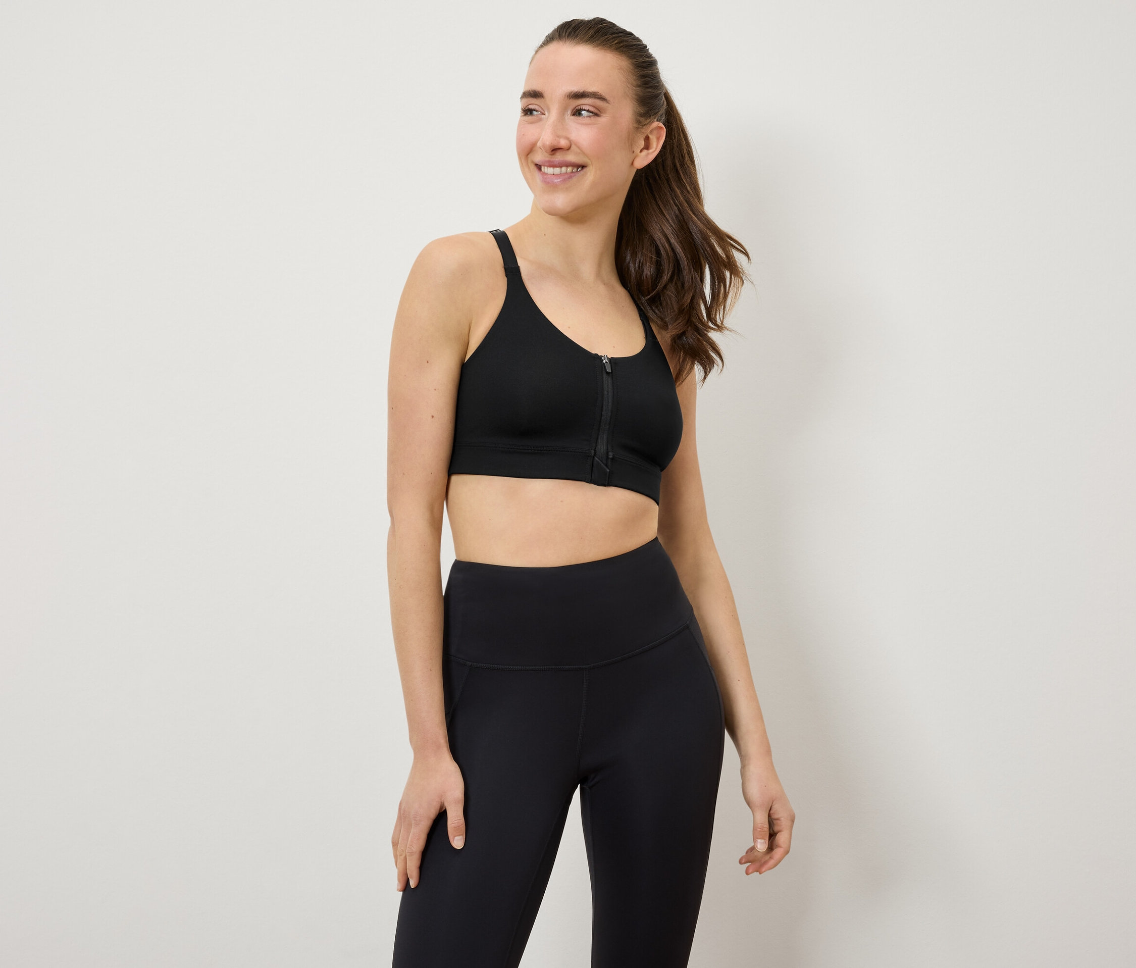 Žena má na sebe čiernu športovú podprsenku a legíny.