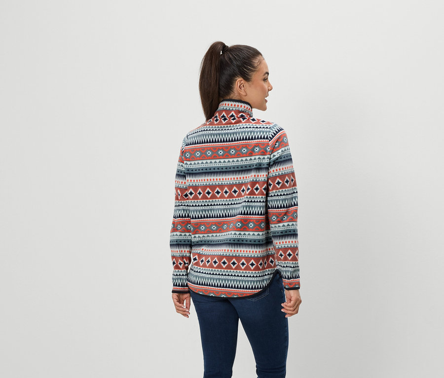 Žena s hnedými vlasmi zopnutými do copu stojí chrbtom a má na sebe modré džínsy a vzorovanú fleecovú mikinu.