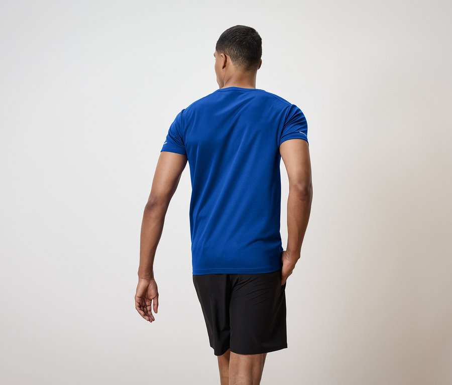 Muž chrbtom ku kamere má na sebe modré tričko a čierne šortky.
