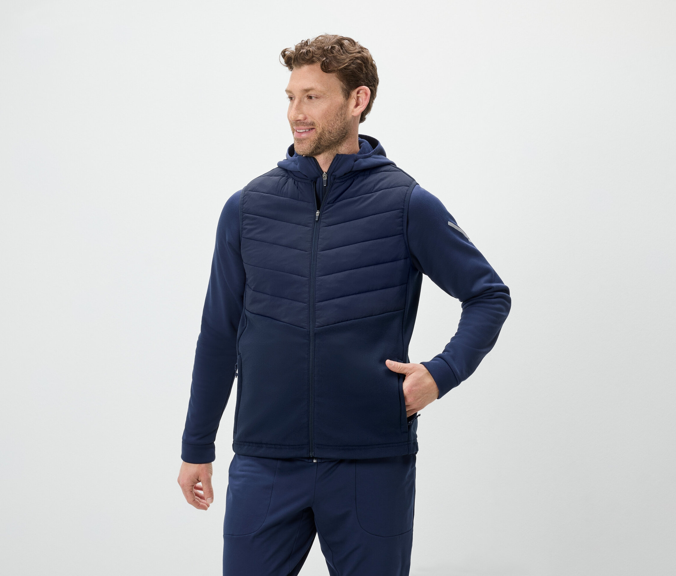 Muž má na sebe modrú vestu s kapucňou a modré tepláky.