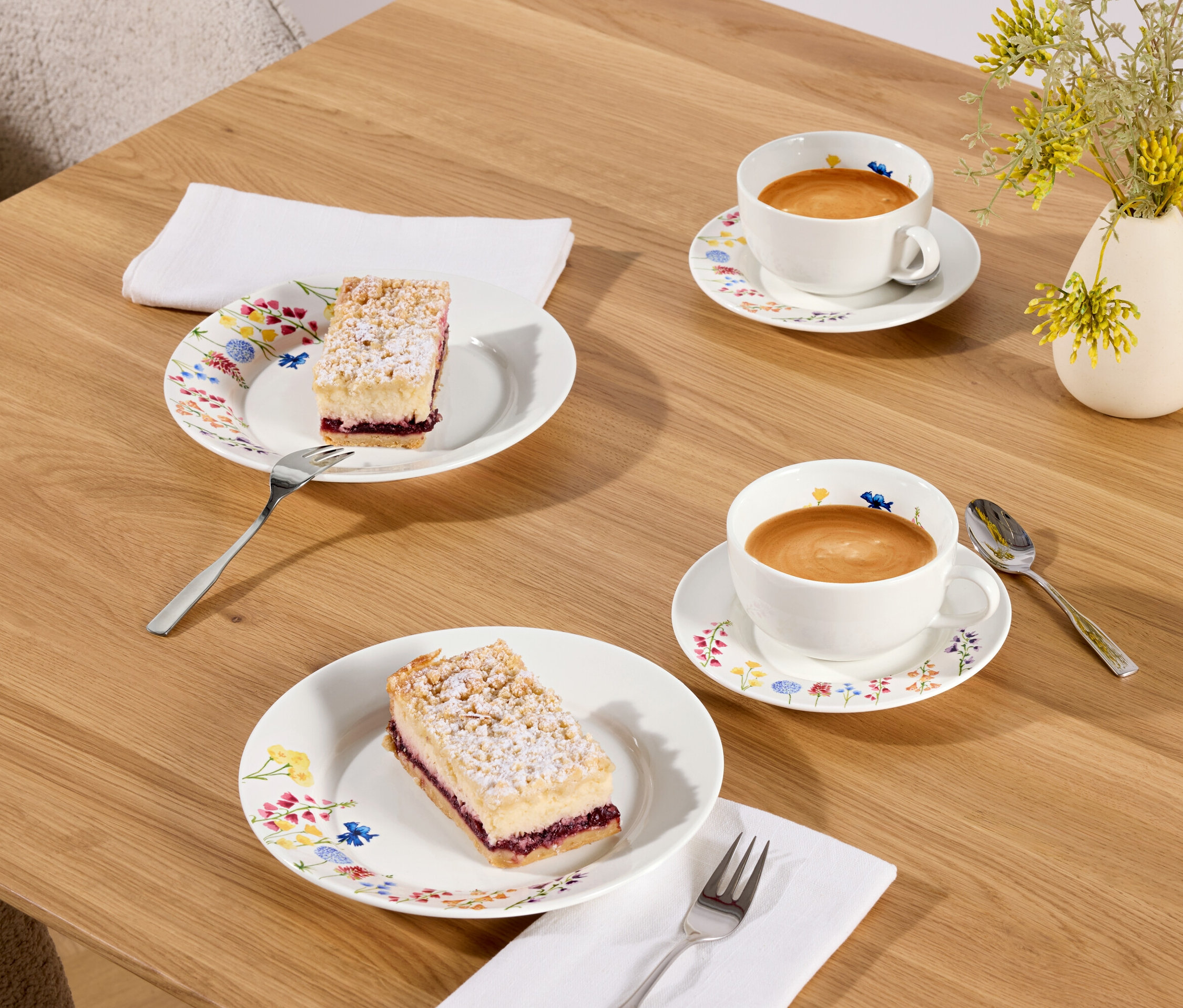 Dva kúsky koláča a dve šálky kávy na drevenom stole.