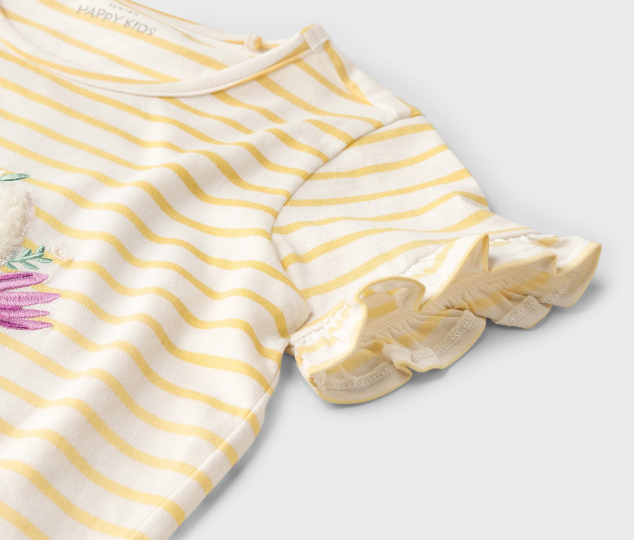 Detail žlto-bieleho pruhovaného trička s krátkym rukávom a fialovým kvetinovým vzorom.