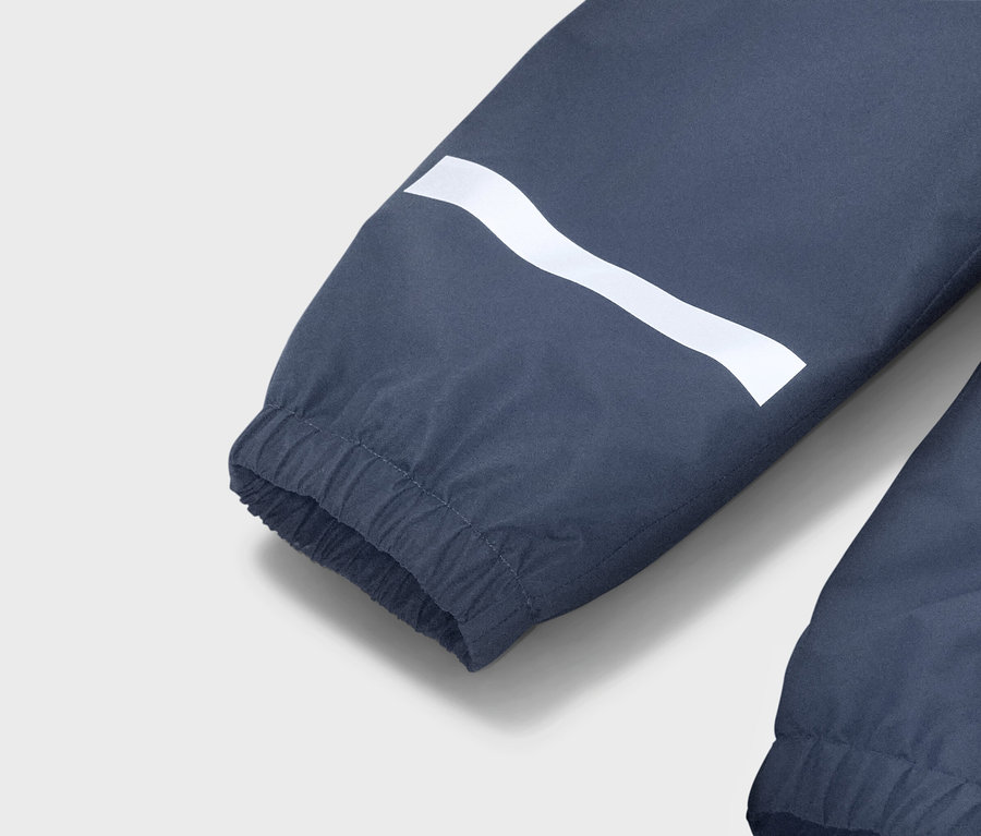 Detailný pohľad na modrý rukáv bundy s bielym vlnitým pruhom a elastickou manžetou.