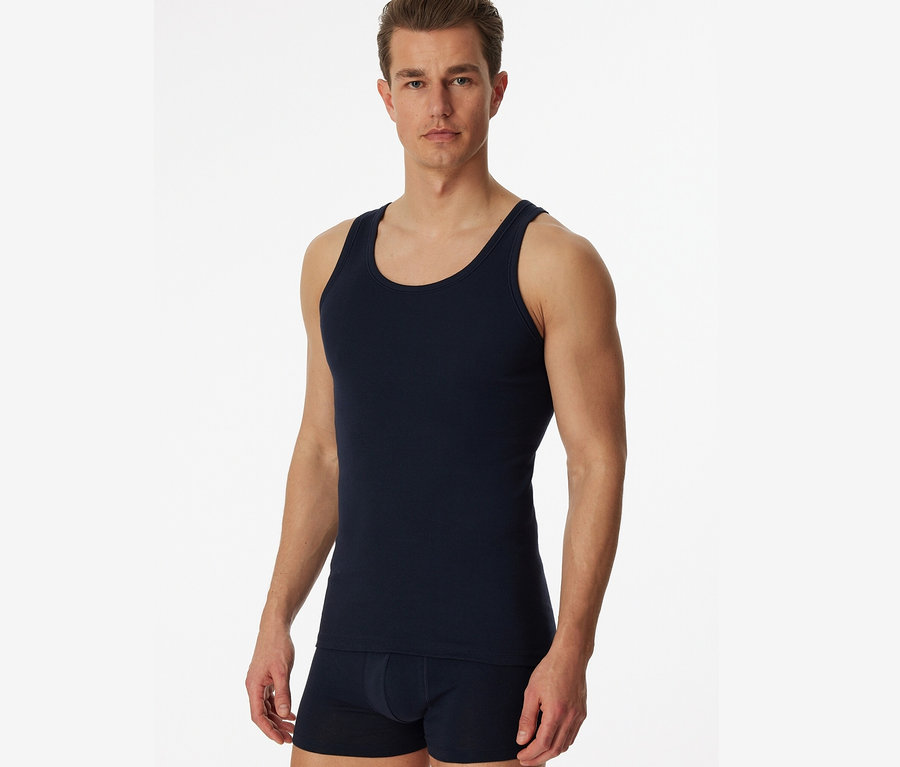 Muž pózuje na bielom pozadí v modrom tielku SCHIESSER s rebrovaným úpletom, 2 ks.