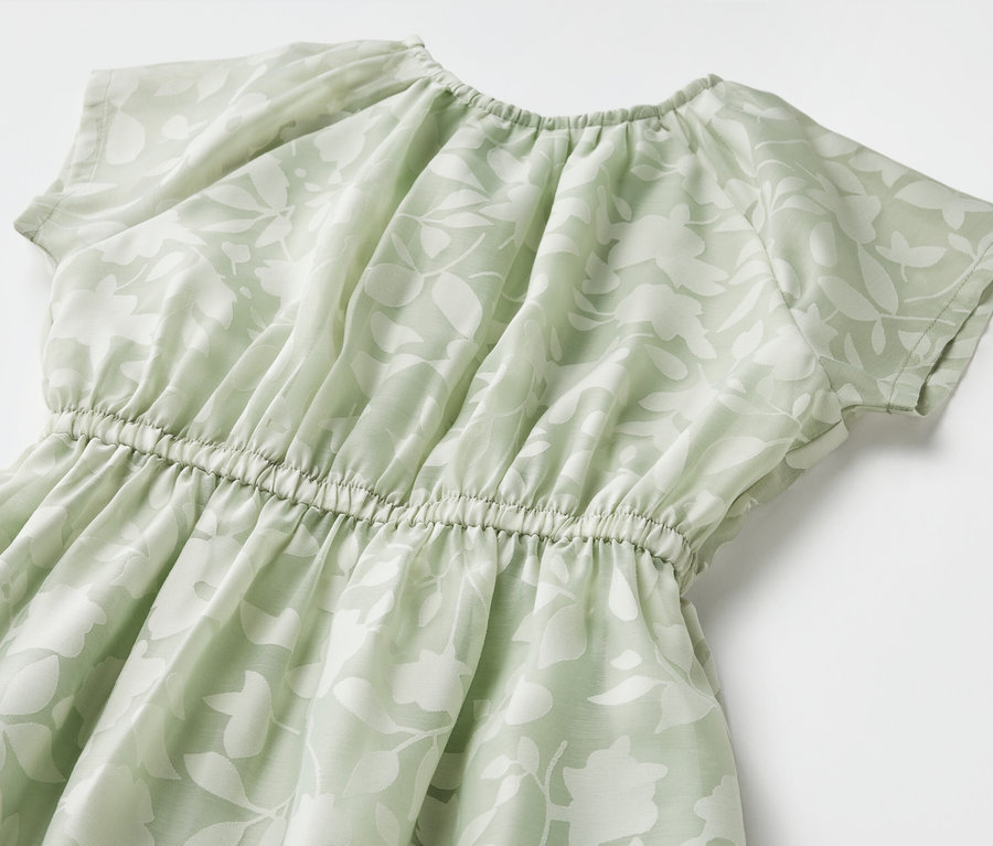 Detailný záber na detské šaty s krátkymi rukávmi a kvetinovým vzorom.