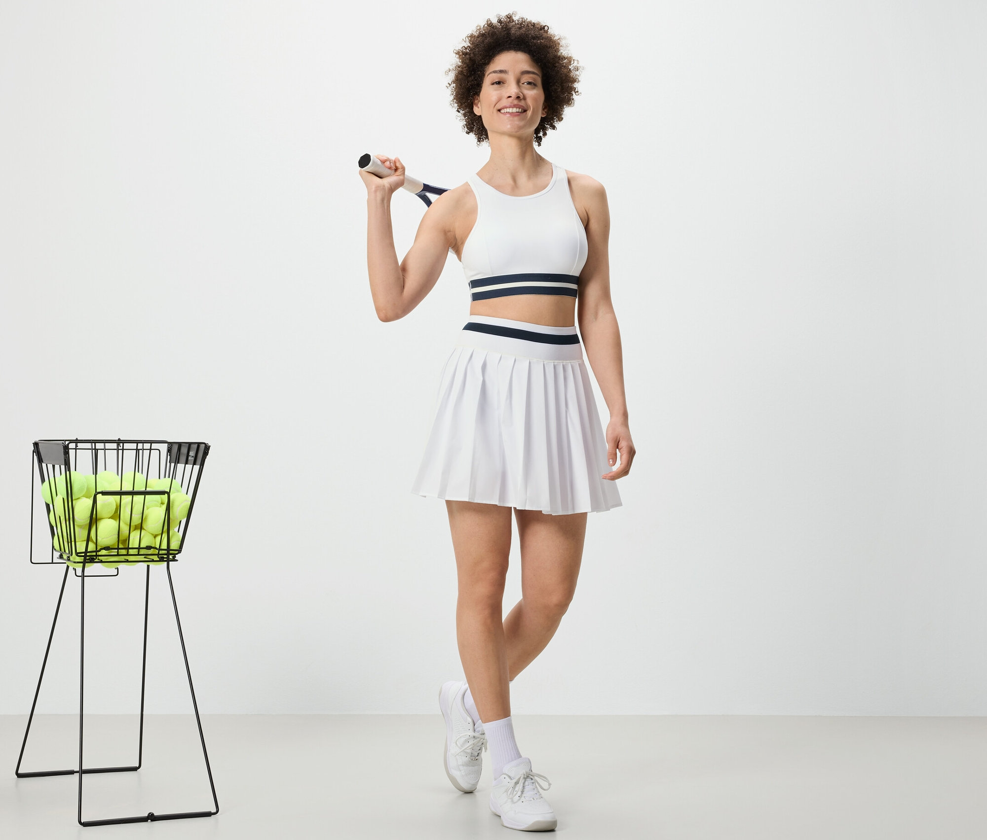 Žena drží tenisovú raketu a má na sebe športovú sukňu.