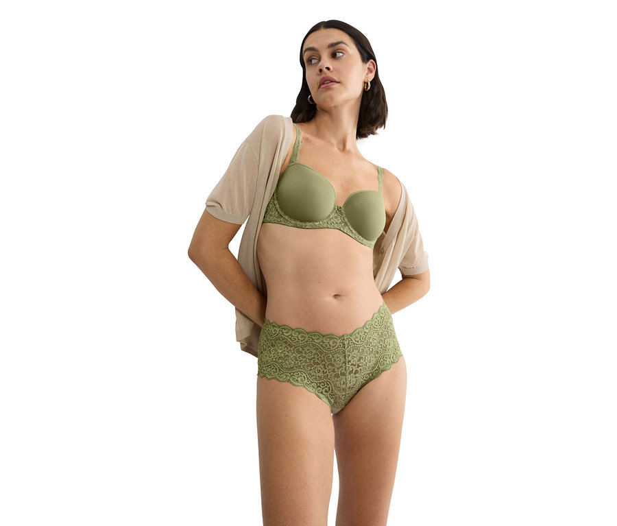 Žena má na sebe zelenú podprsenku s čipkovaným lemovaním a zodpovedajúce čipkované nohavičky a béžový kardigán.