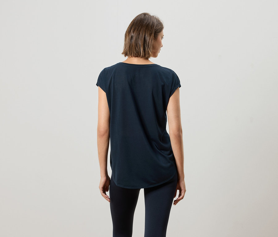 Pohľad zozadu na ženu s krátkymi hnedými vlasmi v tmavomodrom tričku a legínach.