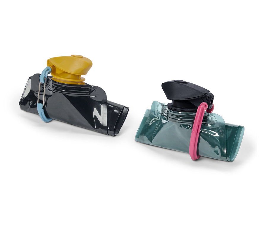 Dva opakovane použiteľné vrecká na výživu, jedno čierne so žltým uzáverom a modrou sponou, druhé modrozelené s čiernym uzáverom a ružovou sponou.