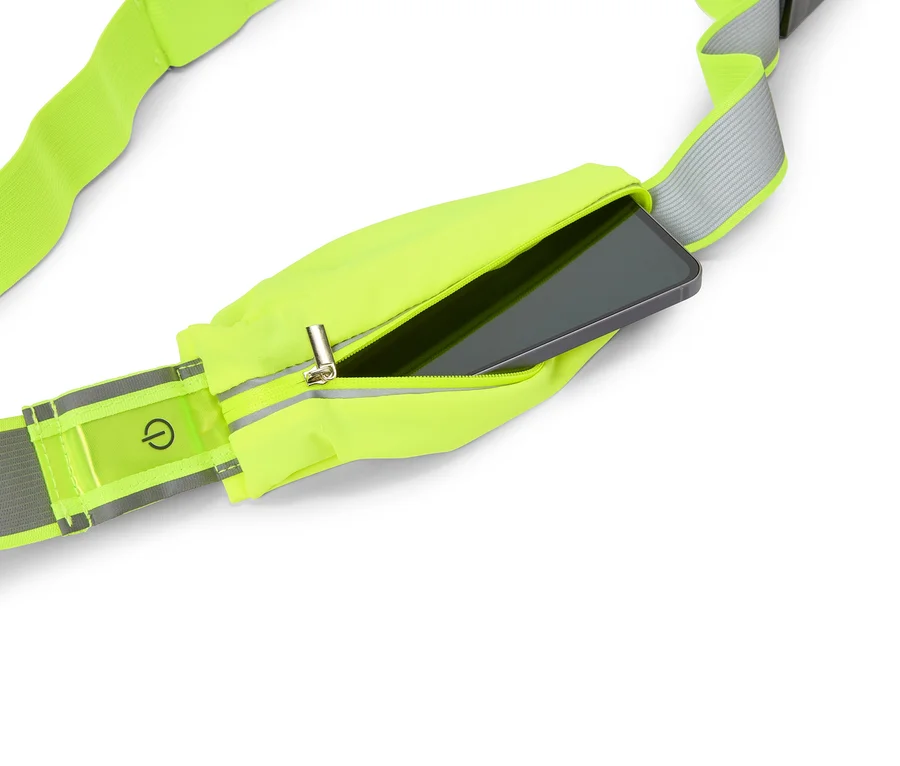Neónovožltý bežecký pás so zipsom, v ktorom je smartfón. Na reflexnom prúžku je viditeľný symbol vypínača.