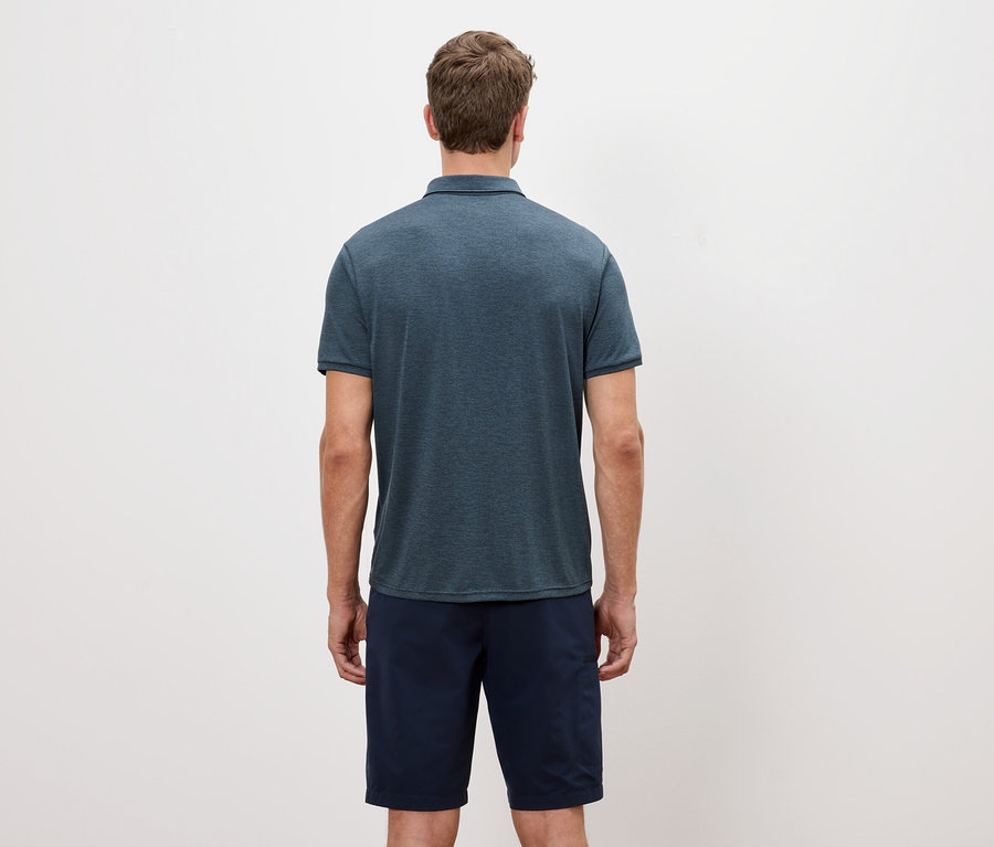Pohľad zozadu na muža v modrošedom polo tričku a šortkách na bielom pozadí.