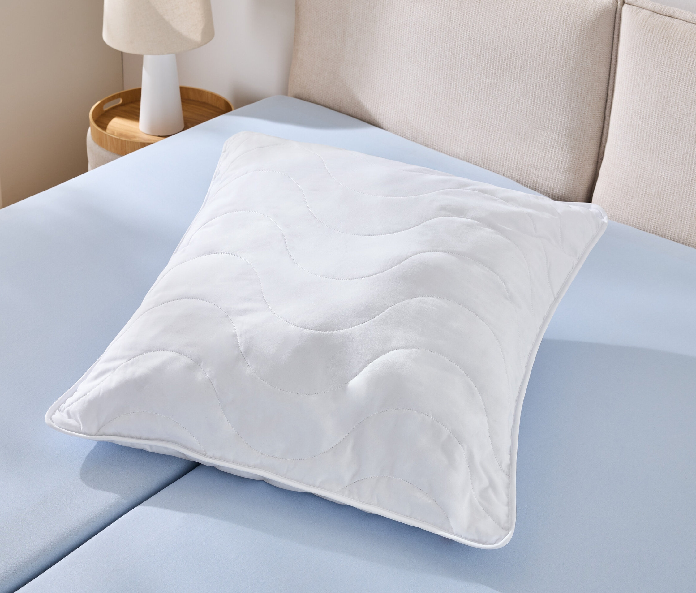 Jeden biely vankúš s možnosťou vyvárania (cca 90 x 70) leží na svetlomodrej plachte.