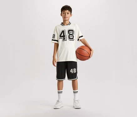 Mladý muž stojí v športovom oblečení a drží basketbalovú loptu.