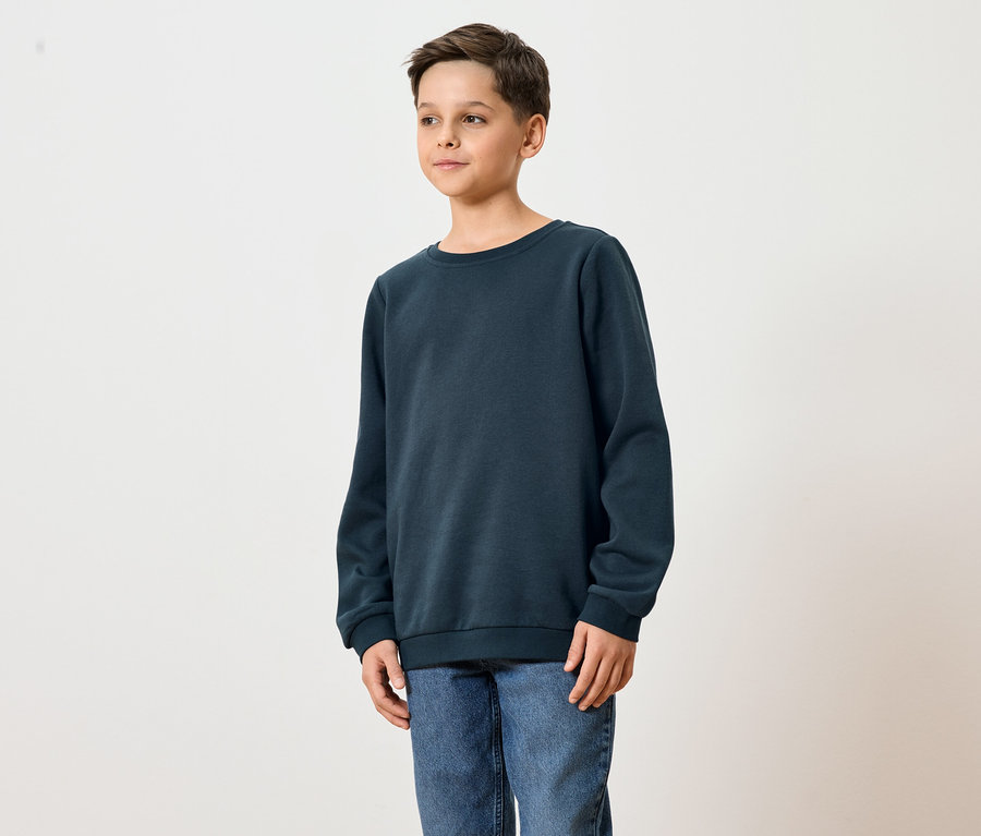 Mladý muž má na sebe tmavomodrú mikinu a džínsy.