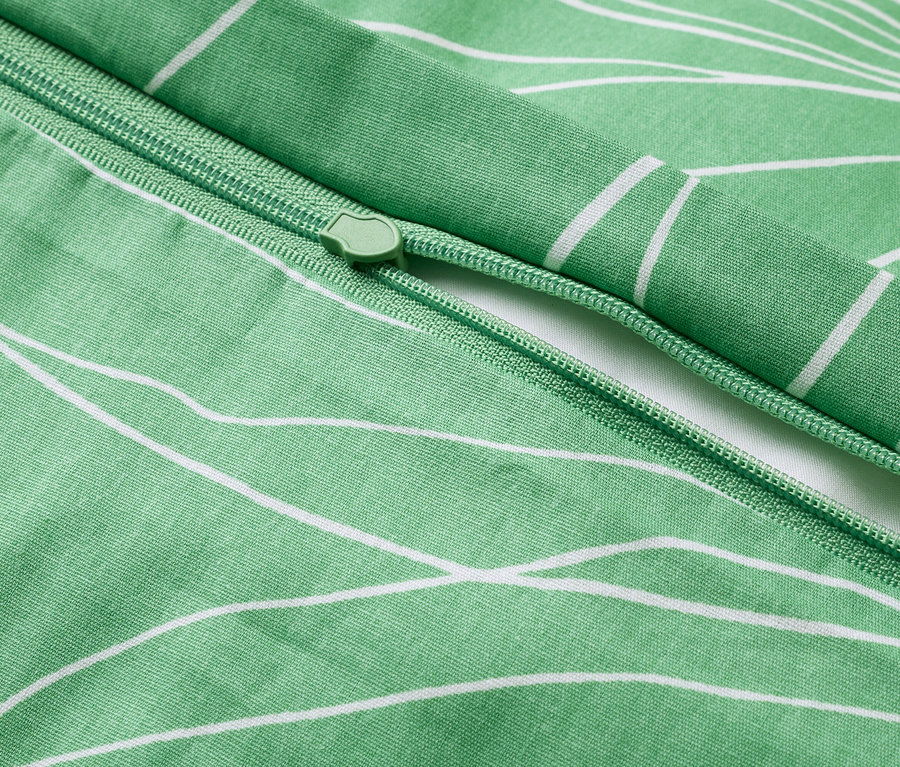 Detailný záber na zelenú obliečku na prikrývku s bielym kvetinovým vzorom so zipsom.