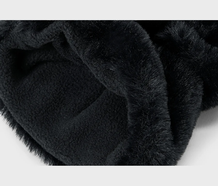 Detail zloženého čierneho materiálu, ktorý ukazuje nadýchanú stranu z umelej kožušiny a mäkšiu, pletenú vnútornú stranu.