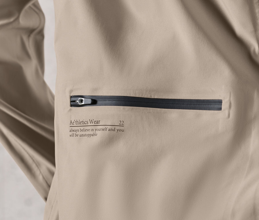 Detail hnedosivej bežeckej bundy do dažďa.