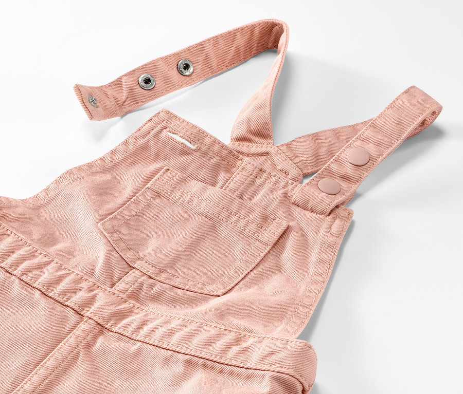 Detail detských šiat s náprsenkou v ružovej farbe.