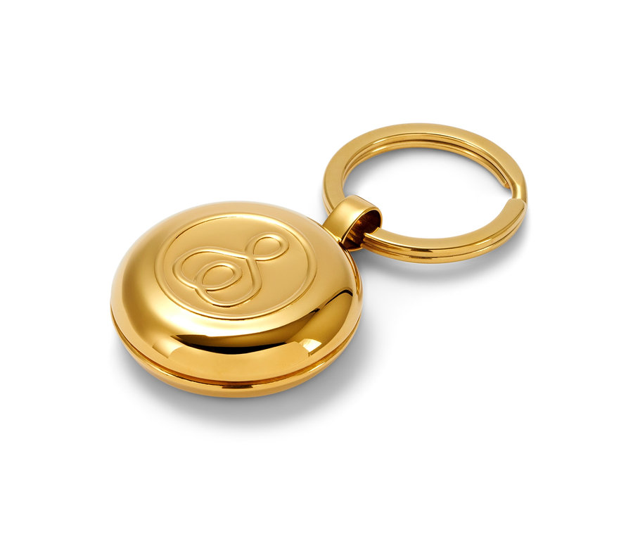 Zlatá kľúčenka s dávkovačom liekov na bielom pozadí.