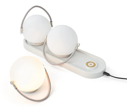 Súprava stolových svietidiel s akumulátorom: Dve lampy na nabíjacej základni a jedna samostatná lampa.