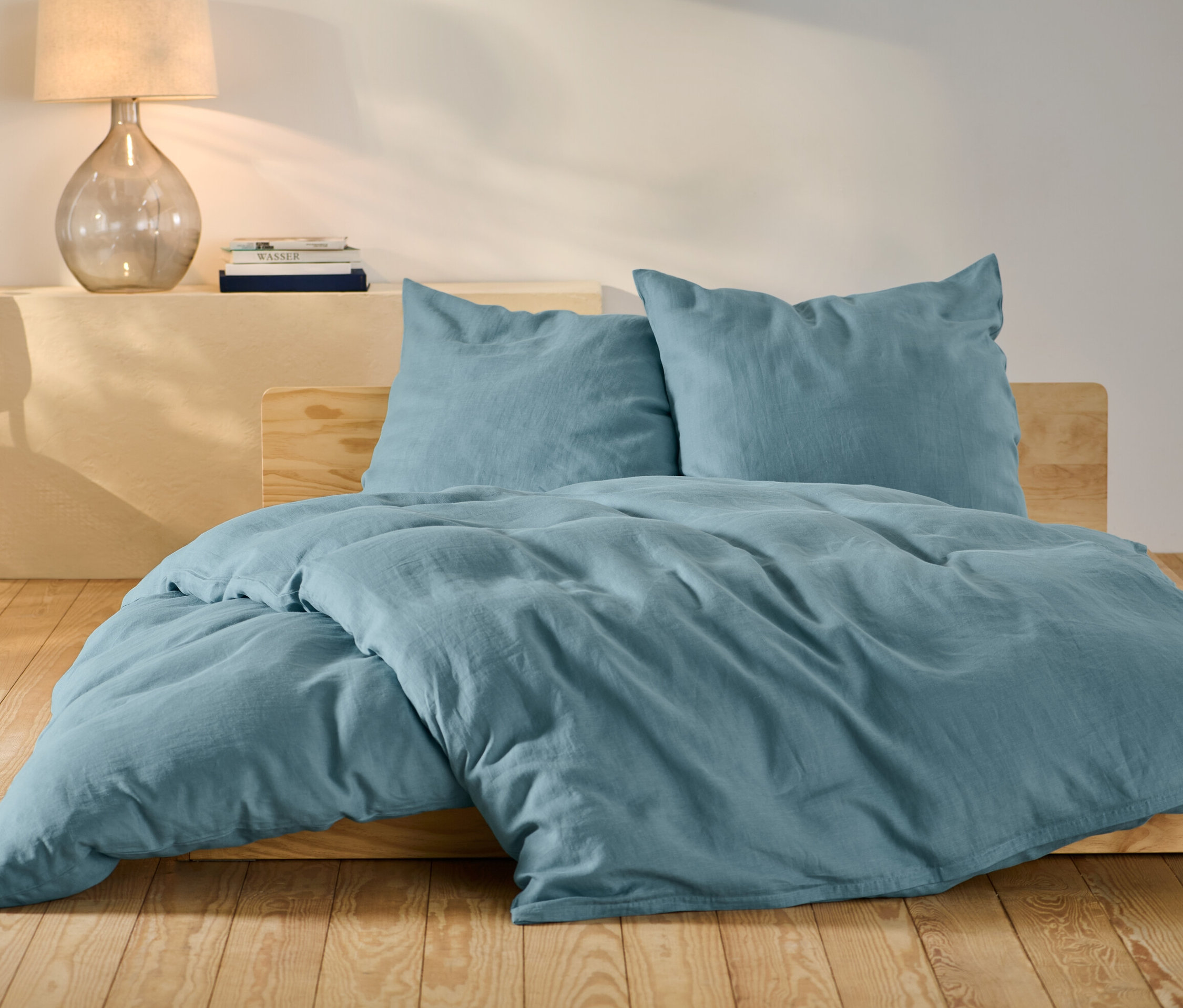 Modrá ľanová posteľná bielizeň štandardnej a nadmernej veľkosti na posteli.