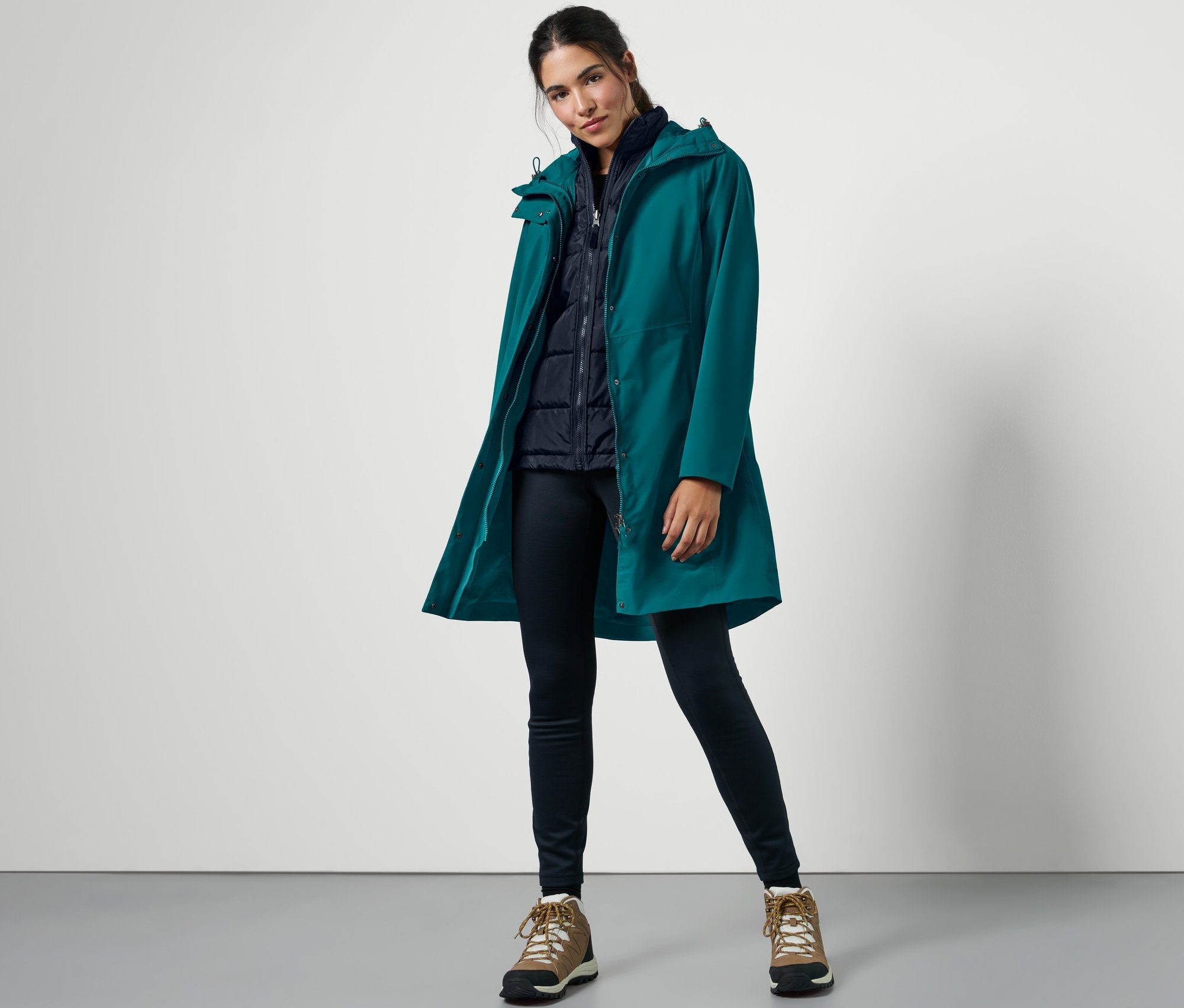 Žena pózuje v petrolejovom outdoorovom kabáte 3 v 1 s vestou.