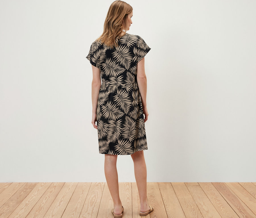 Žena stojí chrbtom k fotoaparátu a má na sebe džersejové šaty s potlačou.