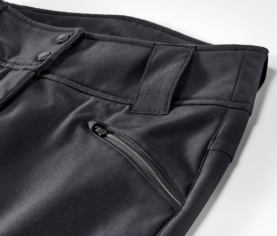 Detail čiernych lyžiarskych nohavíc so zapínaním na gombíky a vreckom na zips.