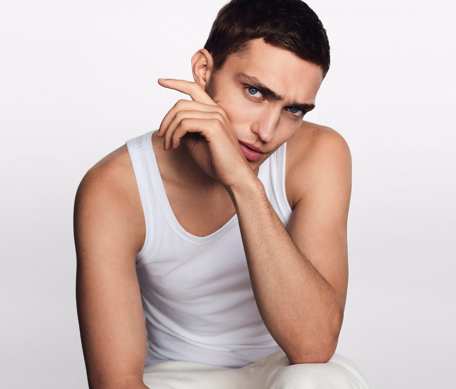 Muž sedí a má ruku pri tvári. Má na sebe biele tielka SCHIESSER s biobavlnou, 2 ks.